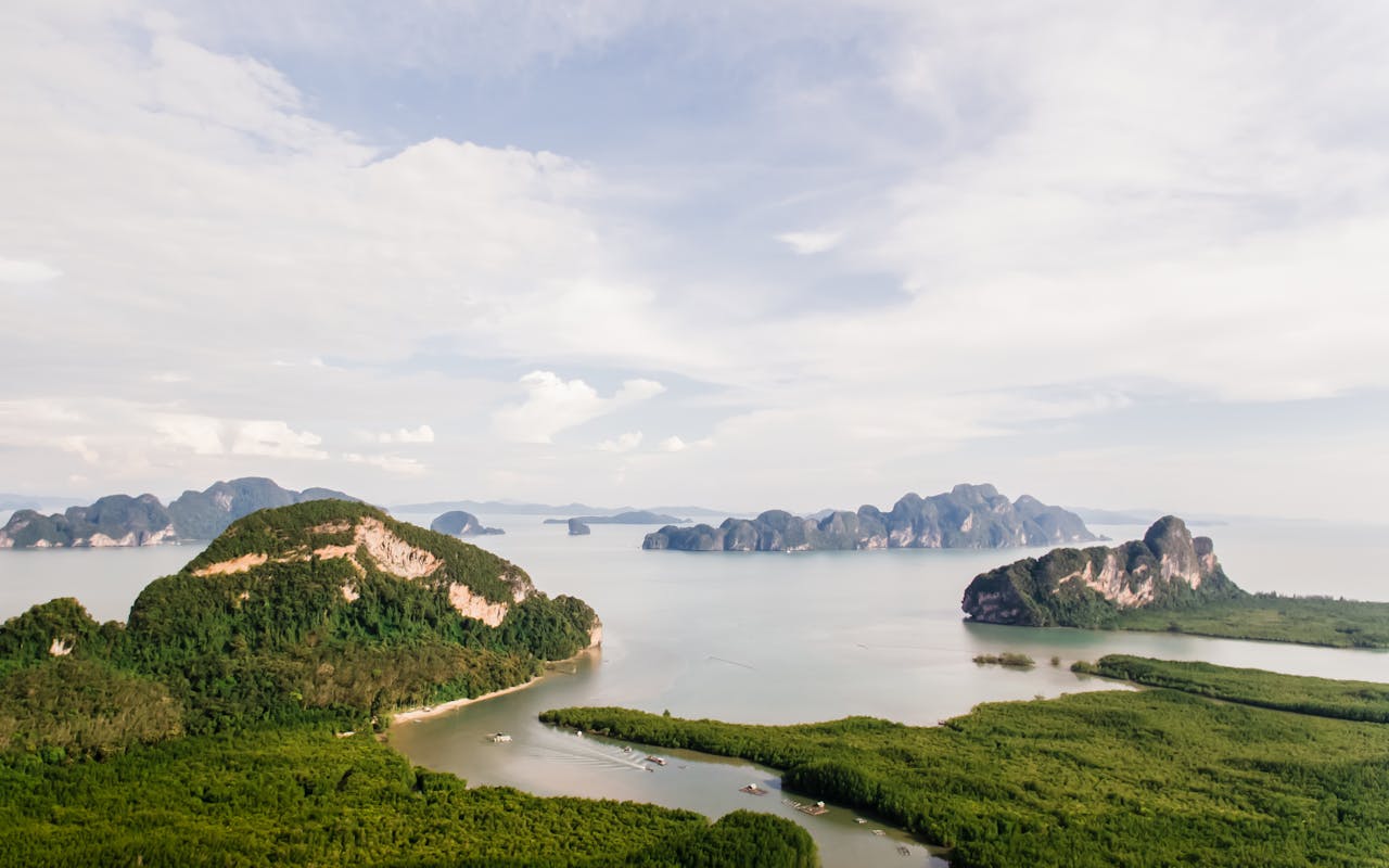 A stunning aerial view of tropical islands surrounded by calm sea and lush greenery under a partly cloudy sky.